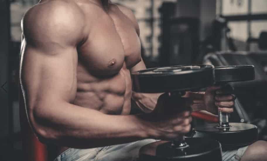 גבר יושב מחזיק משקולות ומבצע אימון כתפיים או אימון יד קדמית