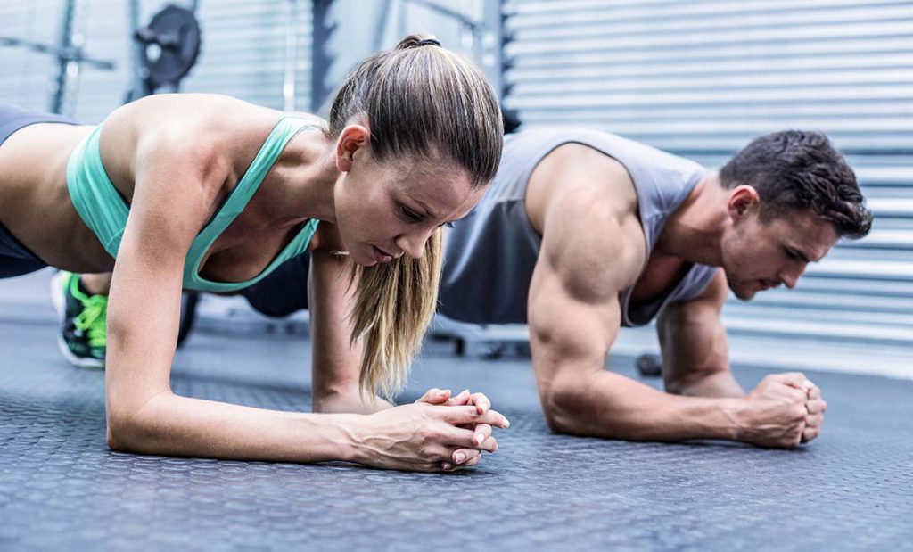 גבר ואישה עם מסת שריר גדולה עובדים על שרירי הבטן