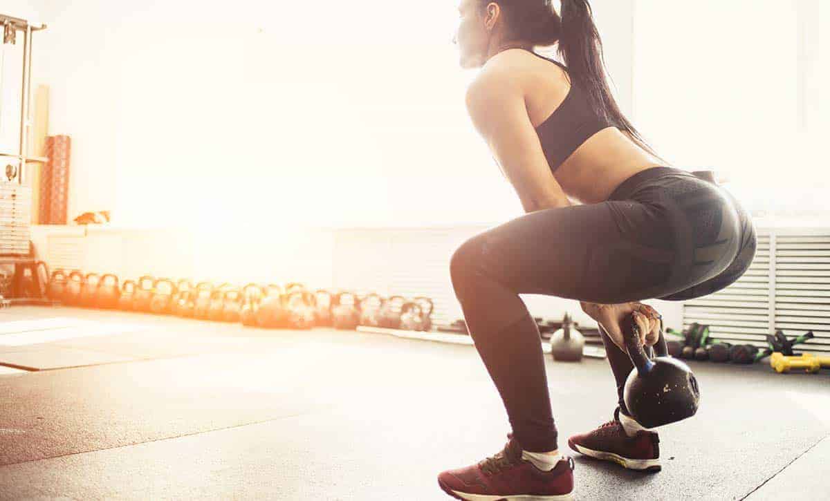 אישה מבצעת תרגיל סווינג עם קטלבל בשעות היום