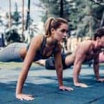 2 נשים וגבר במנח של שכיבת סמיכה עם רגליים באוויר בTRX