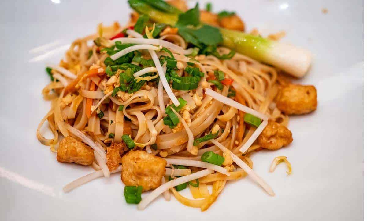 אטריות אורז עם חתיכות טופו מטוגנות, בצל ירוק ובוטנים מלמעלה