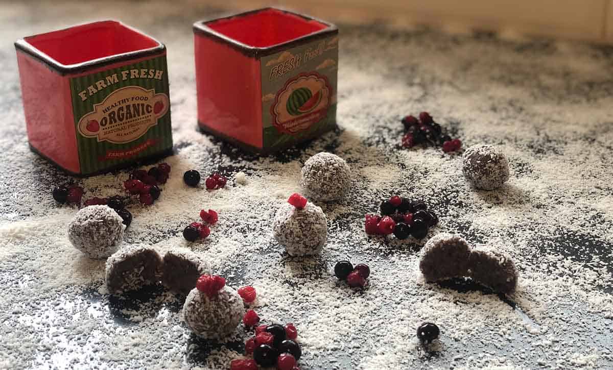 כדורי חלבון התפזורת עם קוקוס מלמעלה ו2 קופסאות אדומות ברקע