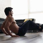 גבר בלי חולצה עם מכנס ארוך מתאמן בבית