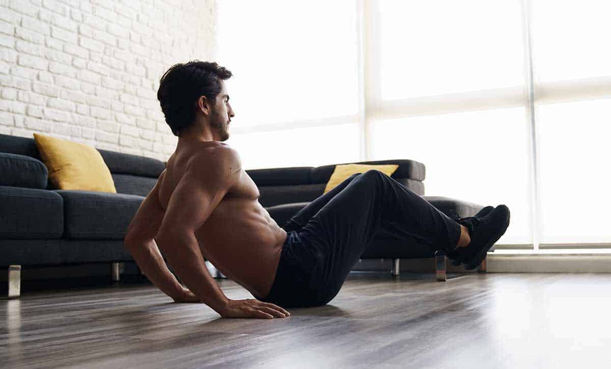 גבר בלי חולצה עם מכנס ארוך מתאמן בבית