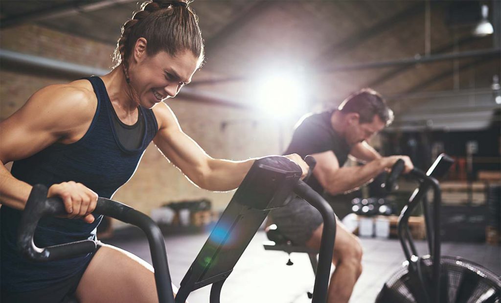 גבר ואישה על אופני כושר מתאמנים בצורה אינטנסיבית