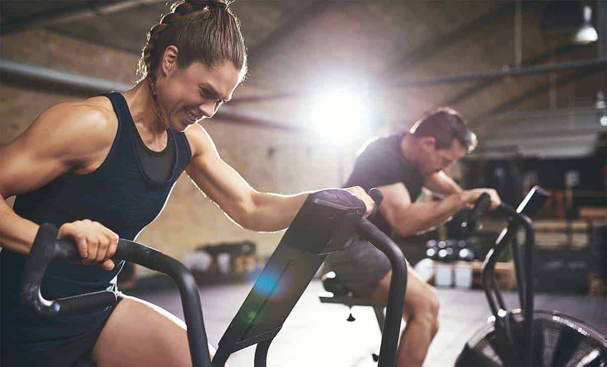 גבר ואישה על אופני כושר מתאמנים בצורה אינטנסיבית