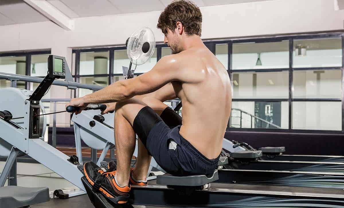 גבר בלי חולצה מתאמן על מכשיר חתירה ומבצע שריפת קלוריות