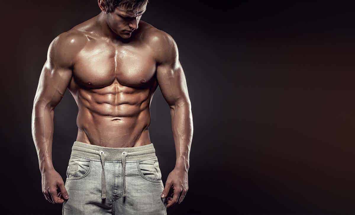 גבר חטוב ושרירי עומד בלי חולצה ומראה את ריבועים, וי קאט, ושרירי חזה וכתפיים