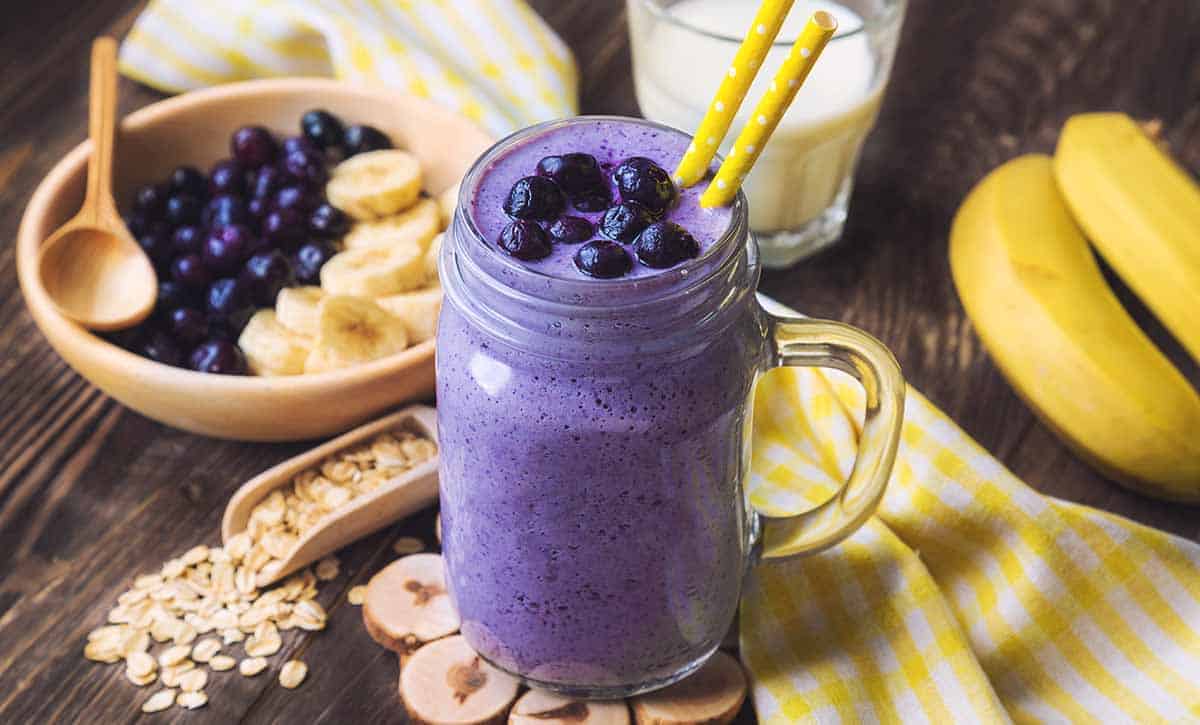 שייק מפירות יער ובננה בתוך כוס עם 2 קשיות